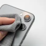 Lente de câmera de celular sendo limpa com um pano de microfibra.